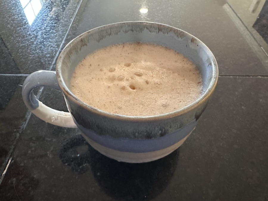 a handmade ceramic mug of hot cocoa on a dark granite counter