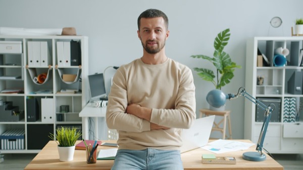a founder posing thoughtfully on a desk in a stock-photo office